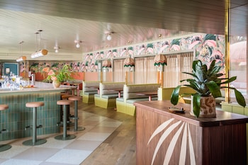 A reception area with a wooden desk, a receptionist, a sofa, two armchairs, and a small table with a lamp. at The Ryder Hotel