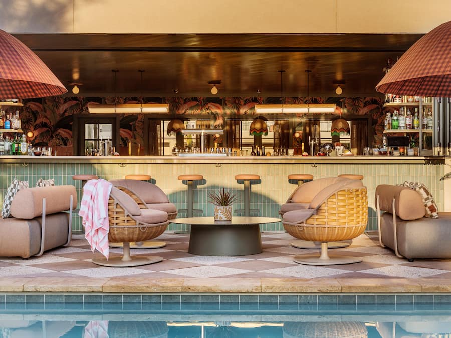 Un área de descanso junto a la piscina con sillas de mimbre, un bar y una piscina.