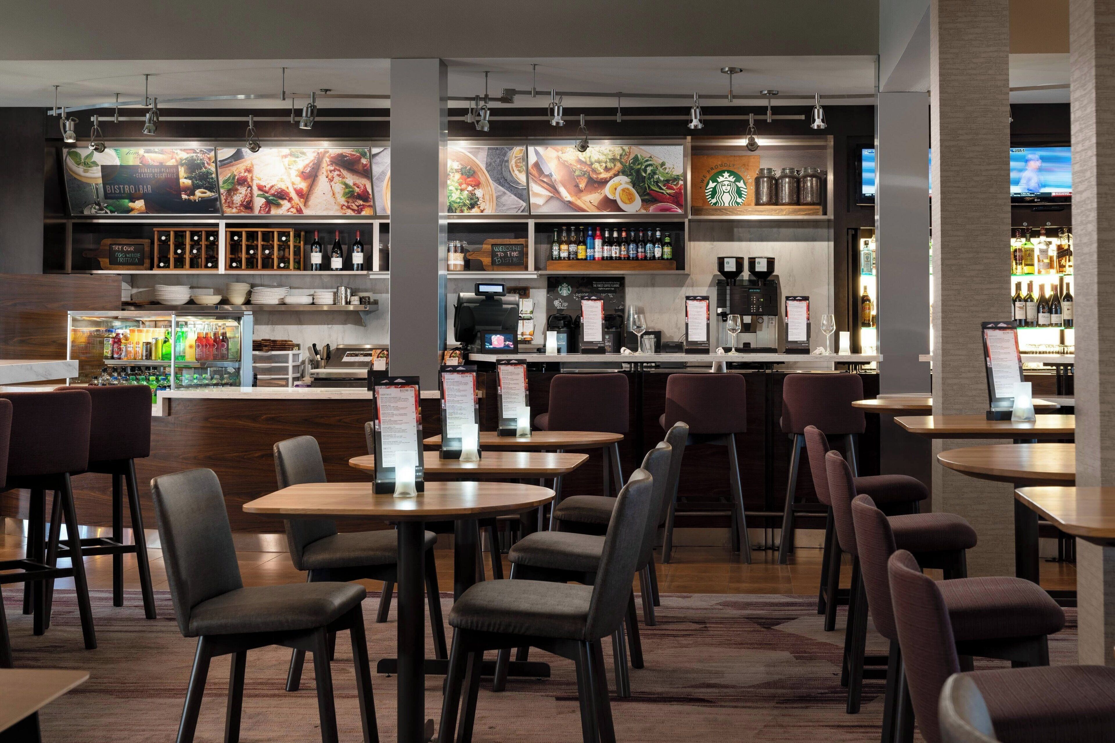 A modern restaurant interior with tables, chairs, a bar area, and a menu display.