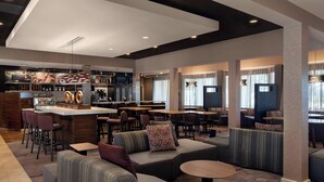 Un espace de détente moderne avec des sièges, un bar et une cuisine en arrière-plan.