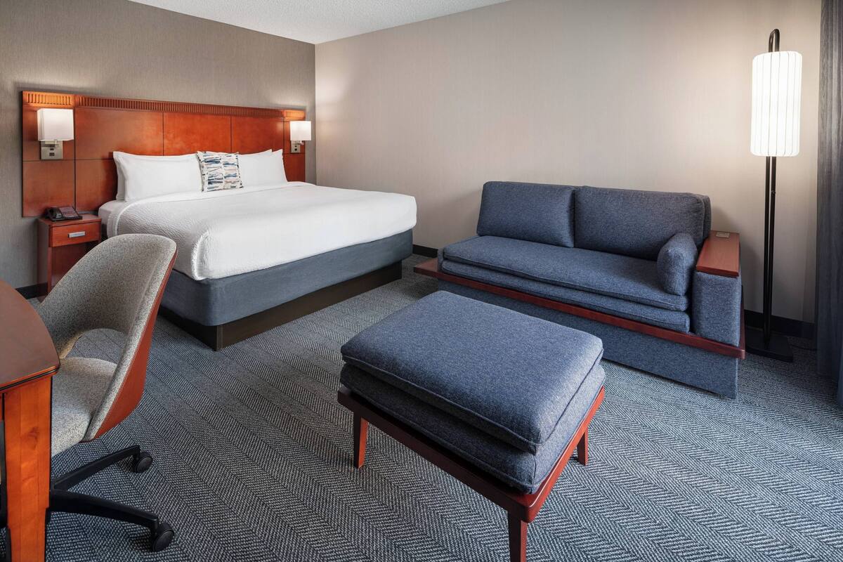 Ein Hotelzimmer mit einem Bett, einem Sofa, einem Sessel und einem Schreibtisch.