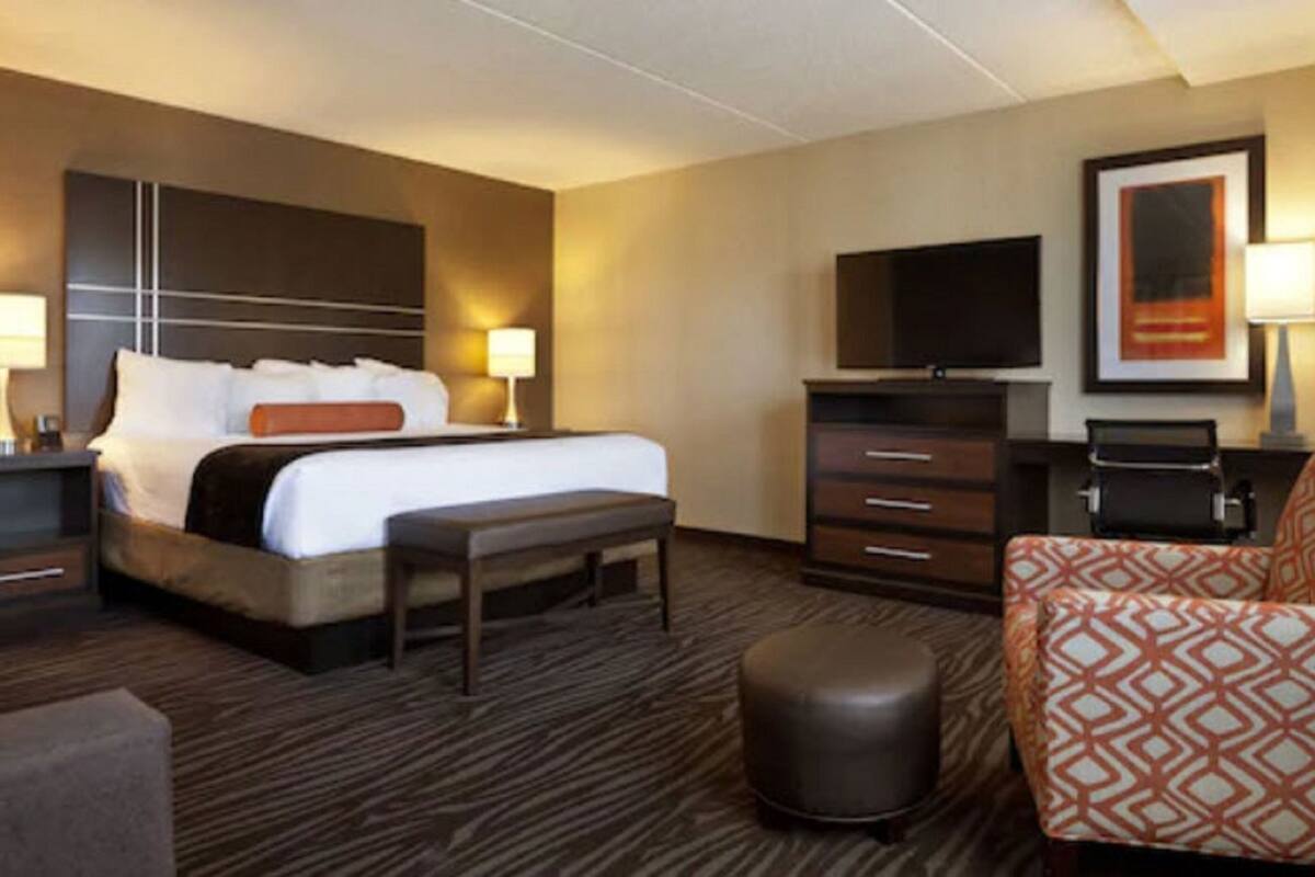 Une chambre d’hôtel équipée d’un lit, d’un bureau, d’une télévision, d’une chaise et d’une poubelle.