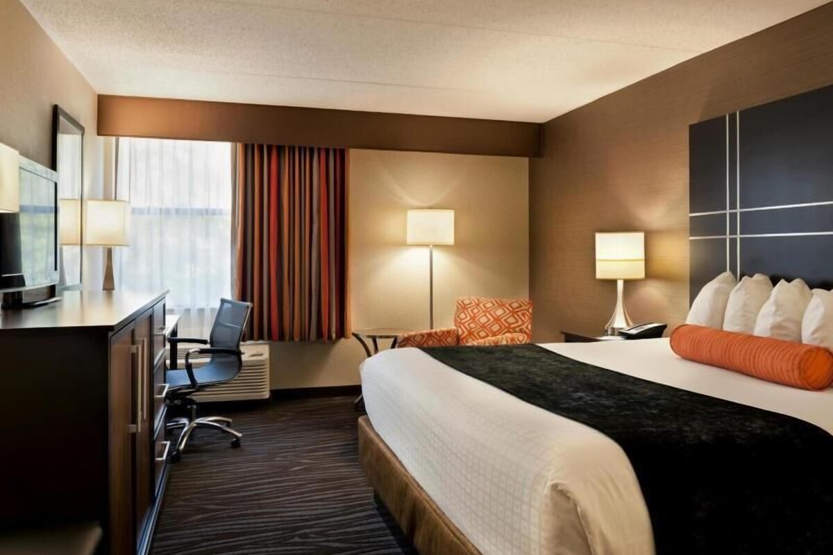 Une chambre d’hôtel équipée d’un lit, d’un bureau, d’une chaise, de lampes et d’un téléviseur.