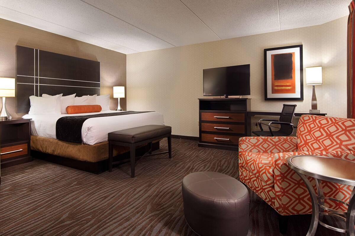 Une chambre d’hôtel comprenant un lit, un bureau, une télévision et un coin salon.