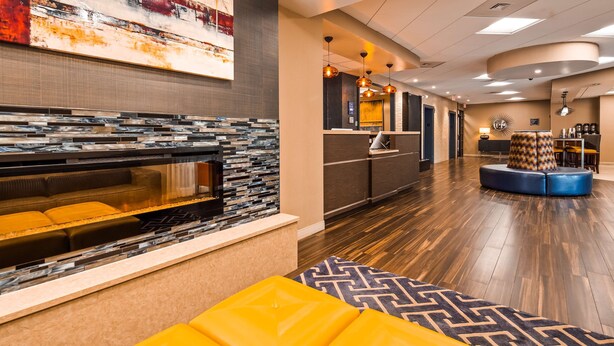 Eine moderne Lobby mit Kamin, Sitzgelegenheiten, Rezeption und einer Kaffeestation.