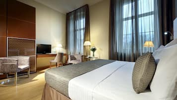 A hotel room with a large bed, a TV, a desk, and two chairs.
