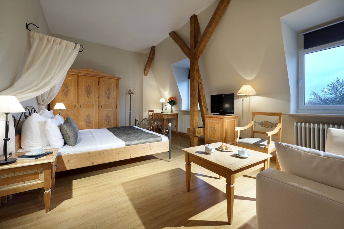 Un dormitorio acogedor con una cama de madera, un escritorio, una silla, un televisor y una ventana con vistas.