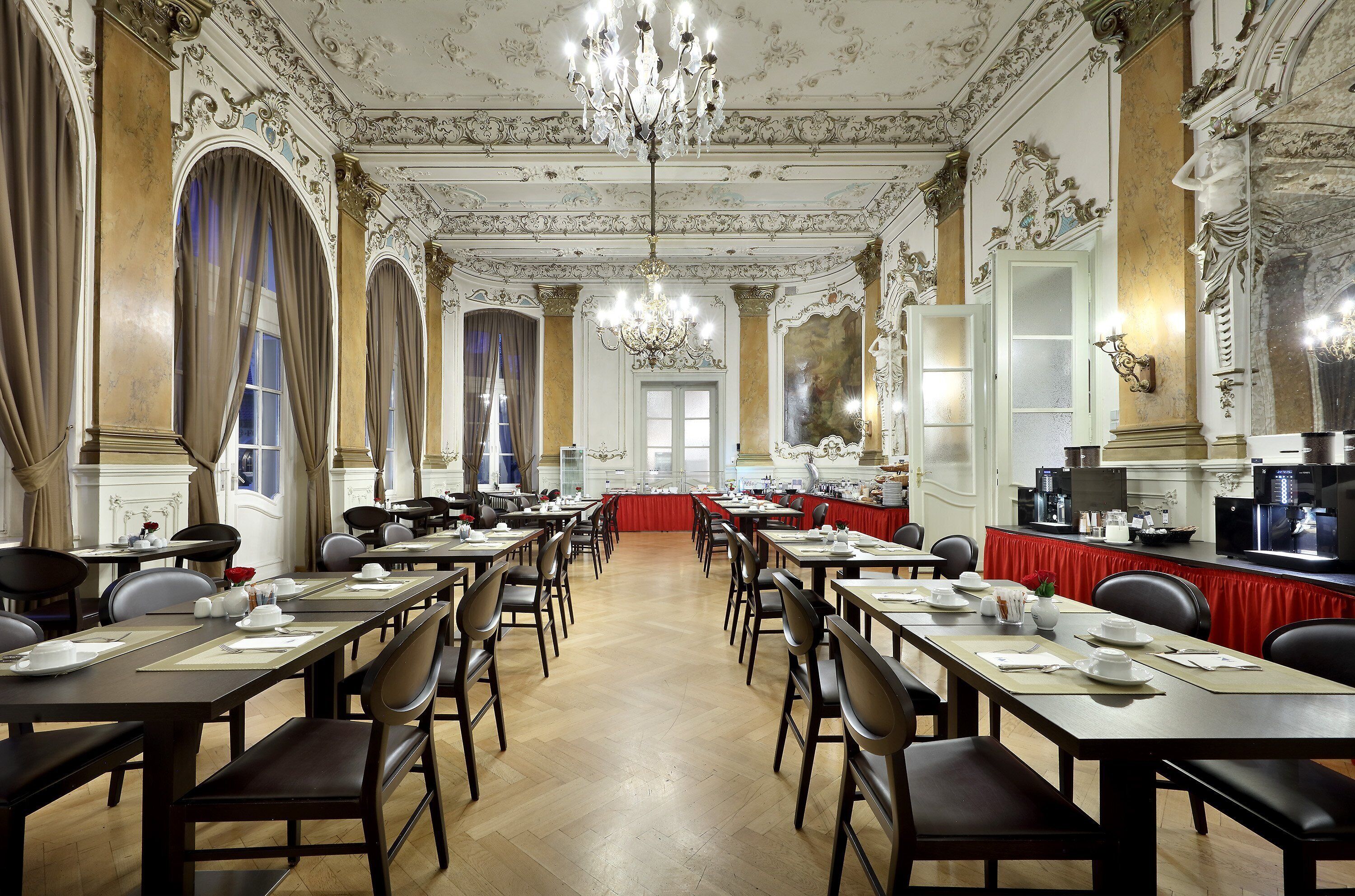 Een statig eetzaal met lange tafels, stoelen, kroonluchters en gedetailleerde wanddecoraties.