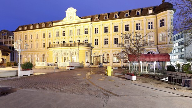 Un edificio histórico con fachada clásica, entrada central y un patio con zonas de estar.