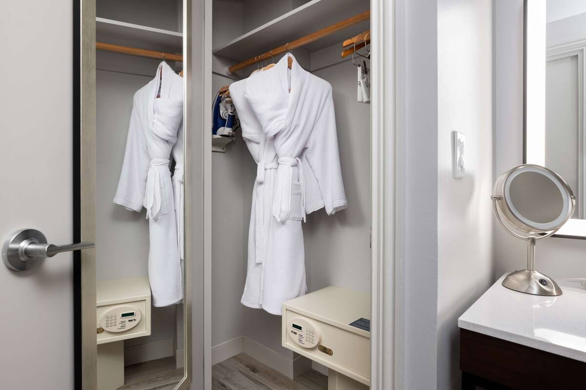 Een badkamer met een spiegel, een badjas en een handdoekrek.