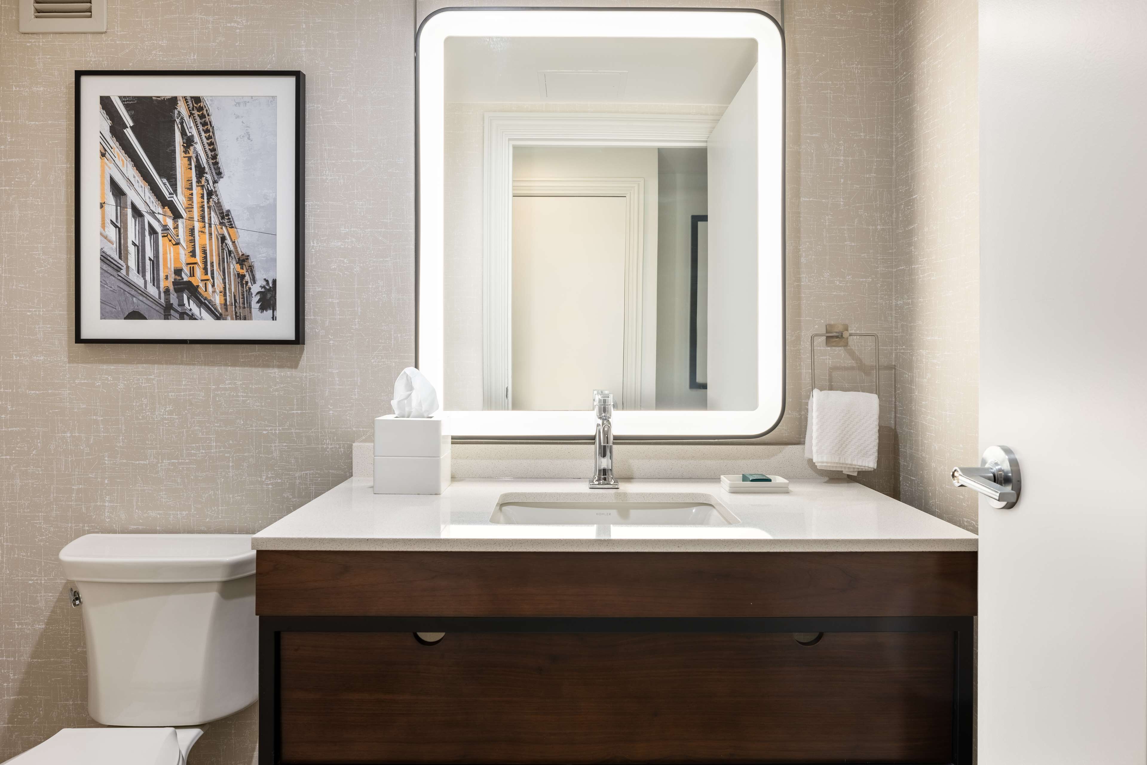 Un baño moderno con un espejo grande, un lavamanos blanco y un mueble de tocador de madera.
