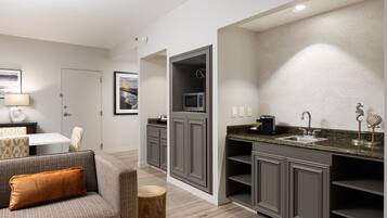 A modern kitchen with grey cabinetry, a built-in microwave, and a stainless steel sink.
