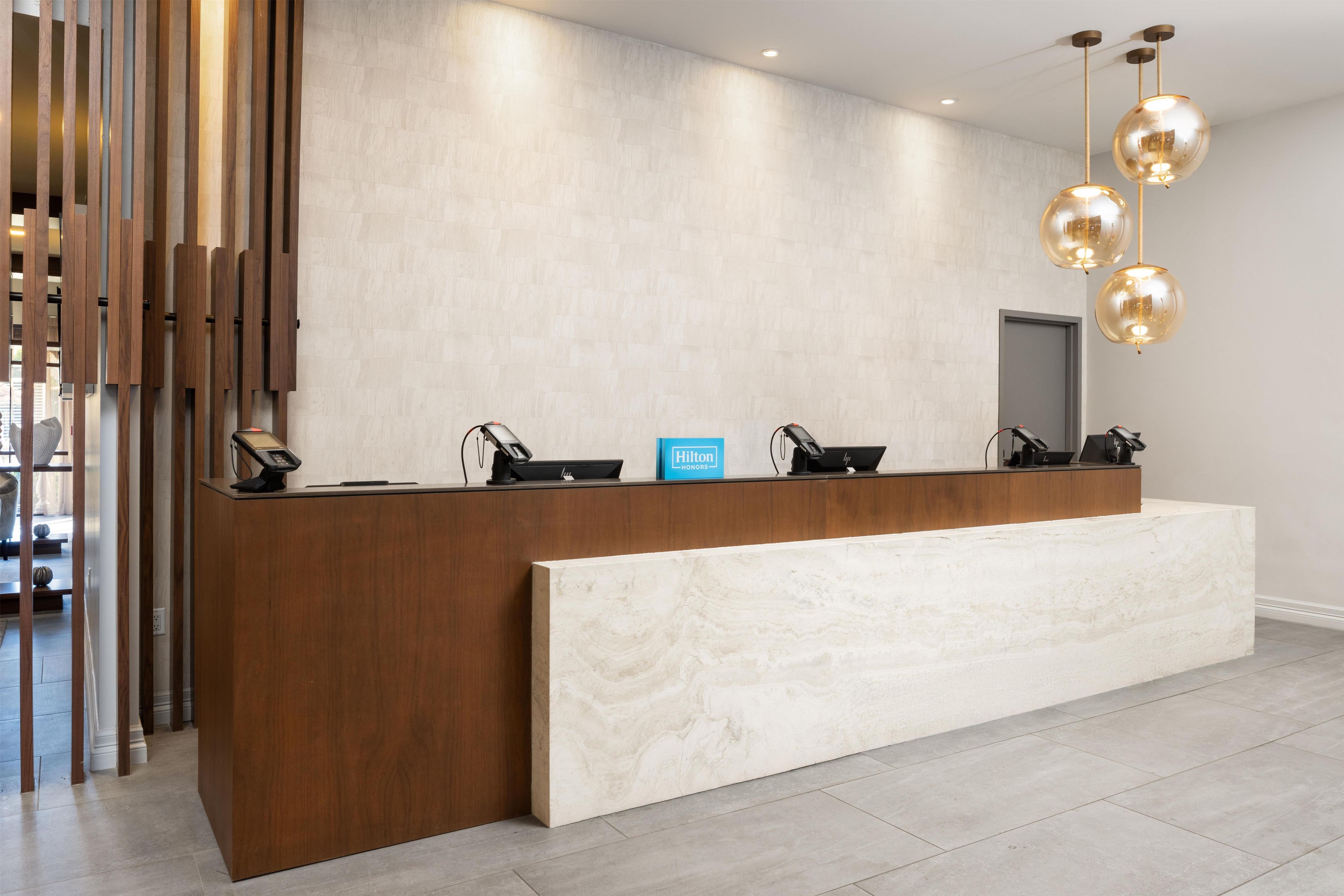 A hotel reception desk with a modern design, featuring a wooden counter and a marble bench.
