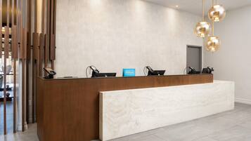 A hotel reception desk with a modern design, featuring a wooden counter and a marble bench.