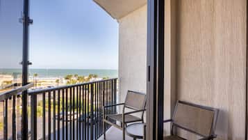 Un balcón con vista al océano y a la playa, con dos sillas y una mesa.