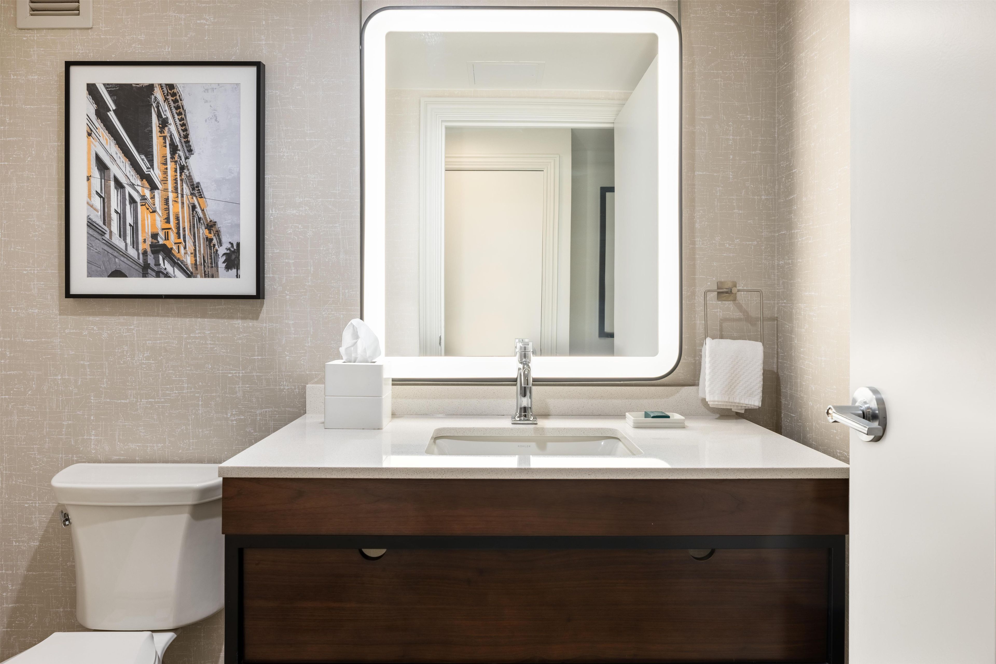 Une salle de bain moderne avec un grand miroir, des toilettes et un lavabo.