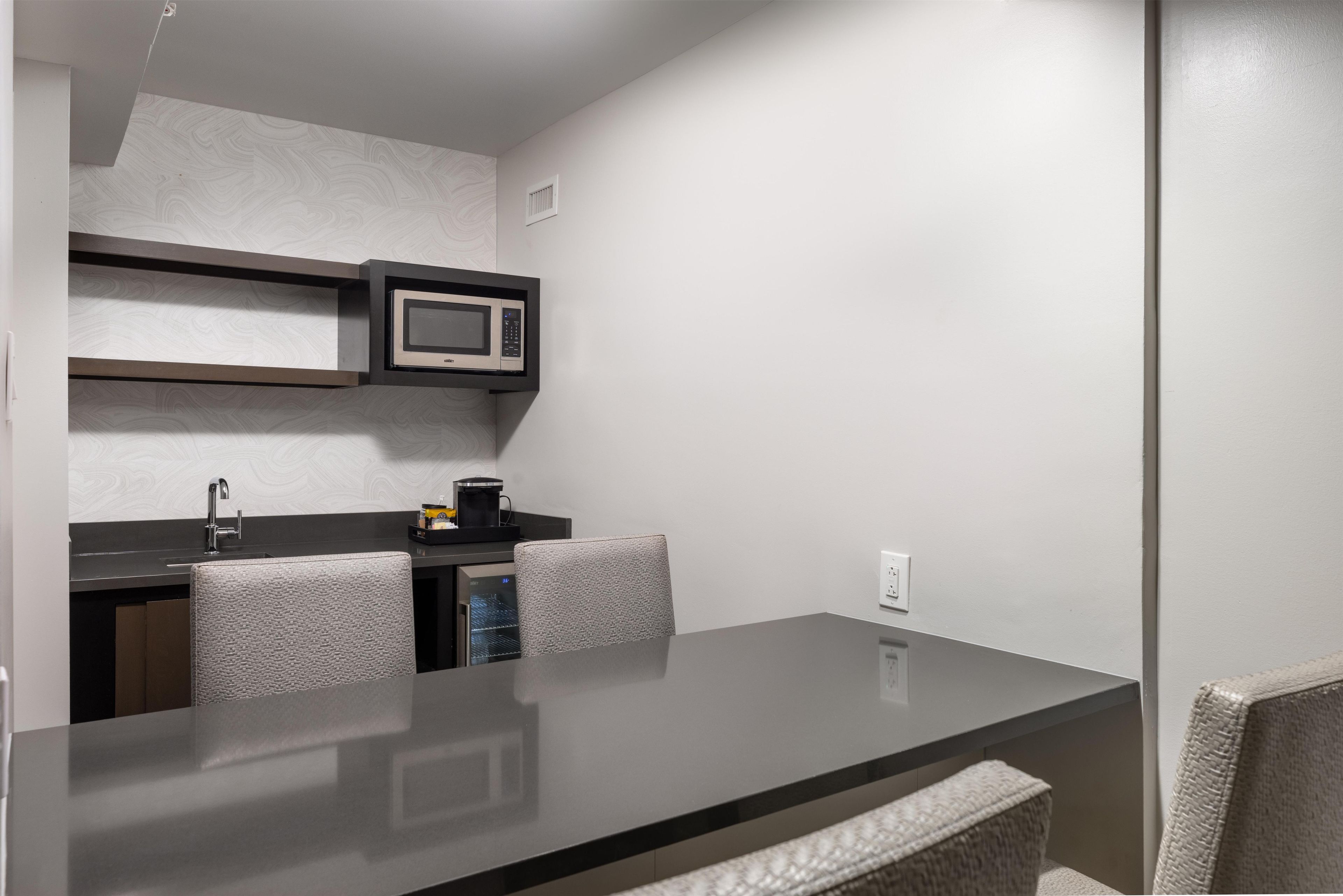 A compact kitchen with a microwave, a coffee maker, and a sink.