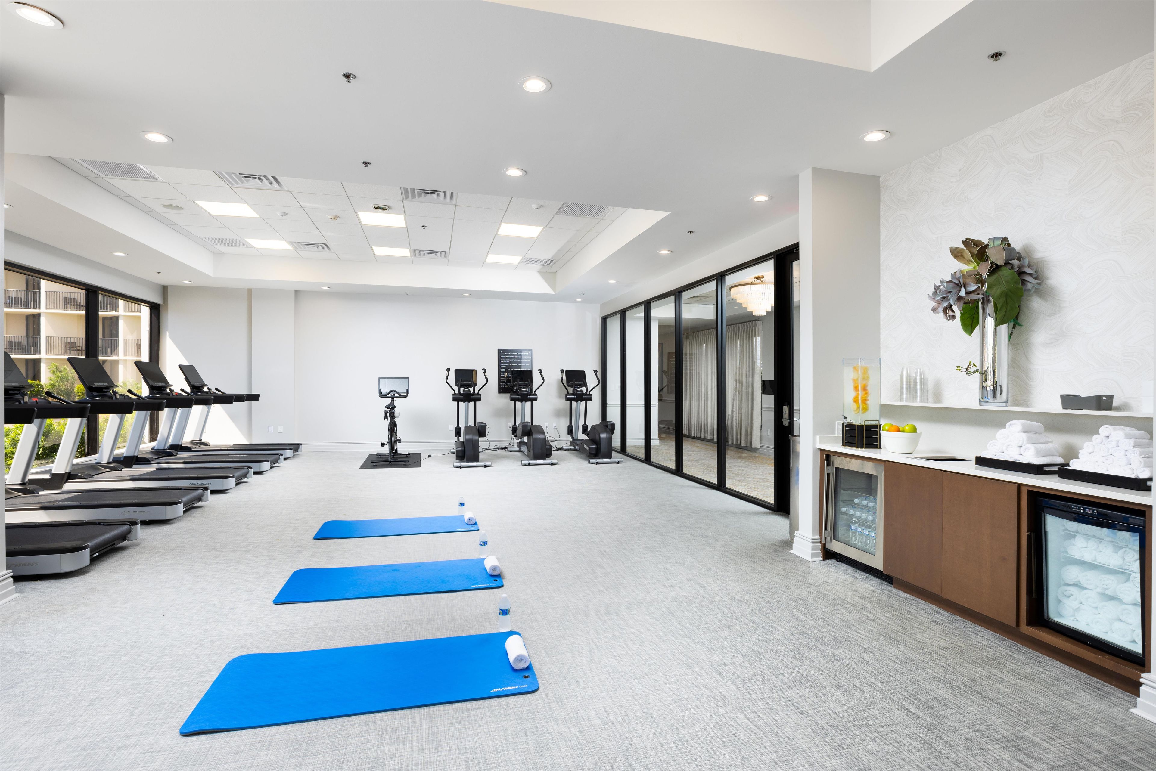 Ein Fitnessraum mit Laufbändern, Ergometer und Yogamatten.