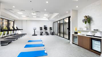 Ein Fitnessraum mit Laufbändern, Ergometer und Yogamatten.