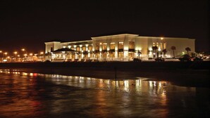 A large, well-lit hotel with a reflective pool in front.