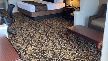Una habitación de hotel con cama, escritorio, silla y alfombra estampada.
