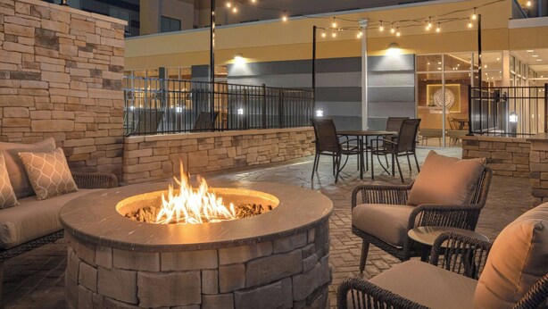 Eine Außenpatio-Terrasse mit einem Steinkamin, Korbmöbeln und Lichterketten.