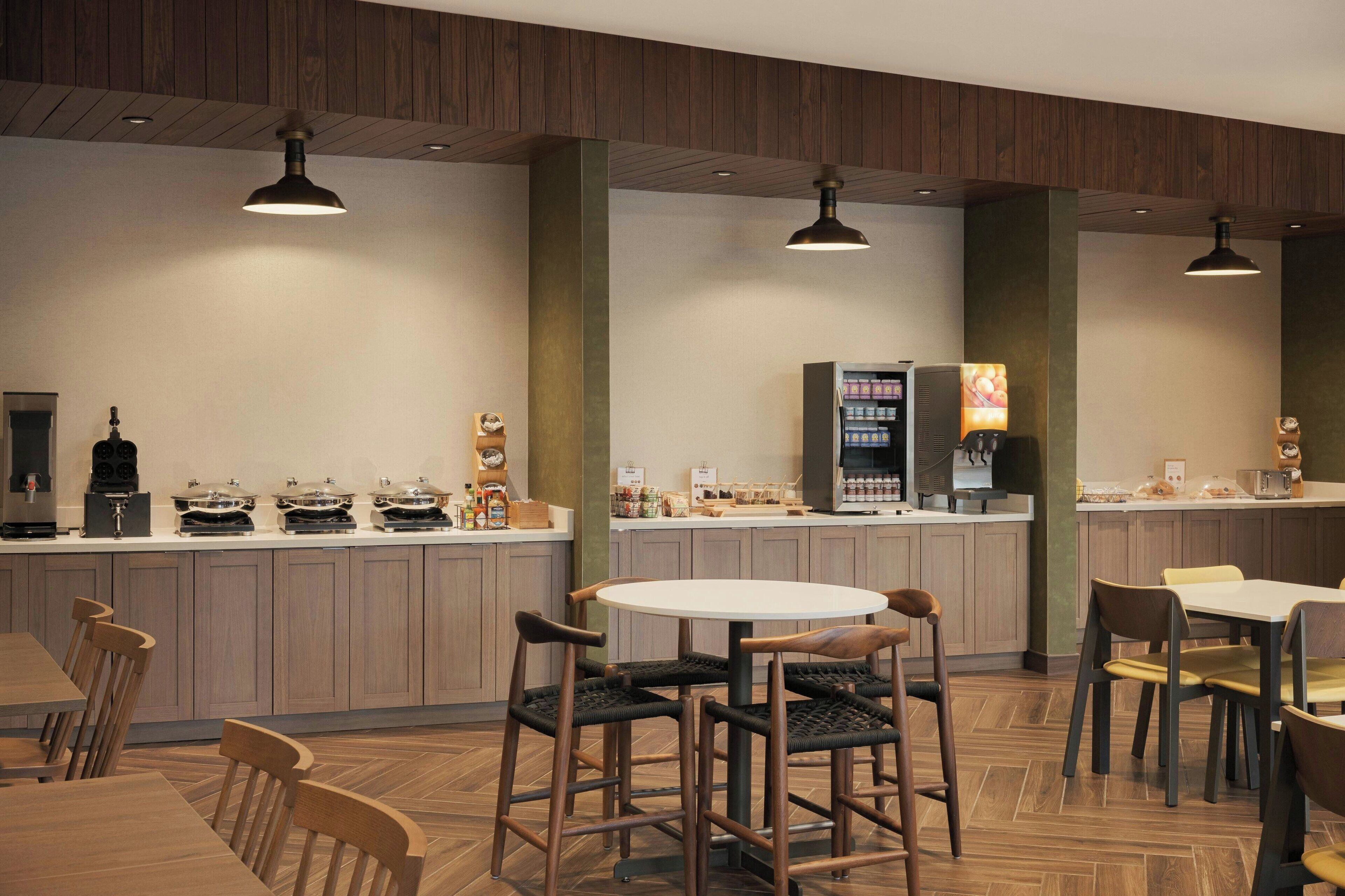 A modern restaurant with wooden paneling, a central island with a coffee machine, and seating arrangements.