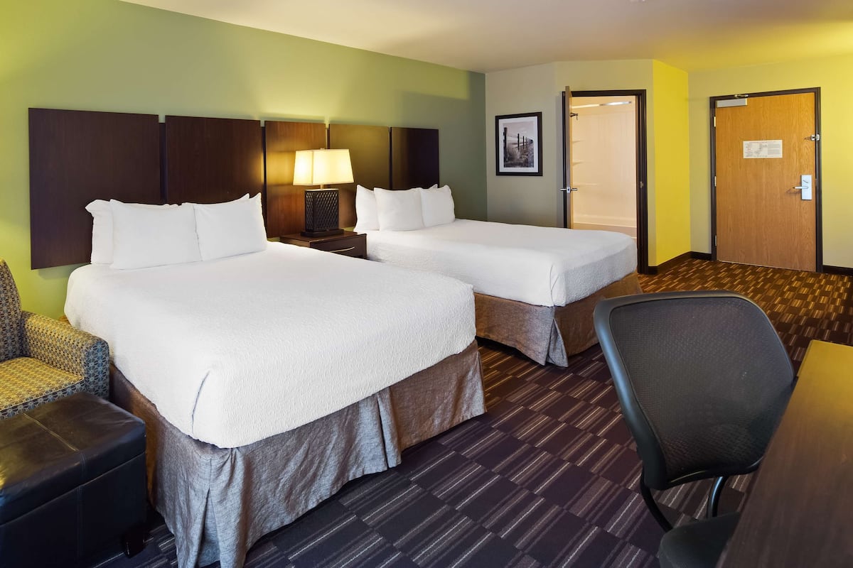 A hotel room with two beds, a sofa, a chair, and a desk.