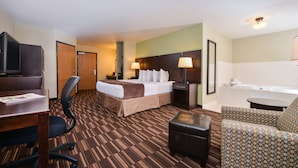 A hotel room with a bed, desk, chair, ottoman, and a sofa.