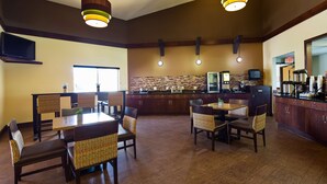 A restaurant with a bar area, seating, and a kitchen in the background.