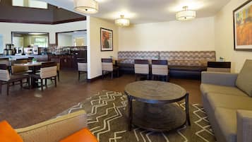 A hotel lobby with a dining area, seating, and a bar.