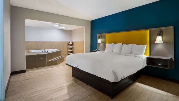 A modern hotel room with a large bed, a built-in bathtub, and a separate shower area. - Best Western Bordentown Inn (Bordentown)