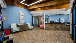Un vestíbulo amplio con suelo de madera, un mostrador de recepción y zonas de estar.