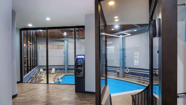 Un área de piscina interior moderna con un separador de vidrio, suelo de madera y un cajero automático.