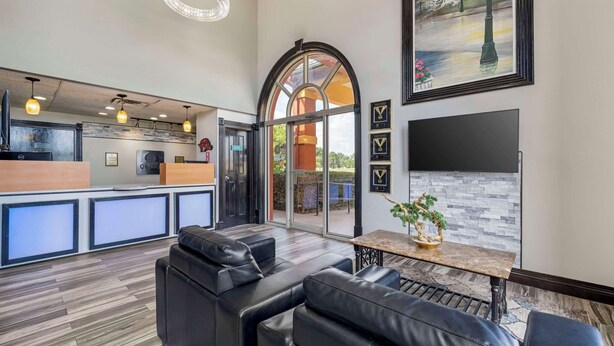 A modern hotel lobby with a reception desk, leather seating area, and a large window with a view of the outdoors. - Quality Inn Siloam Springs West (Siloam Springs)