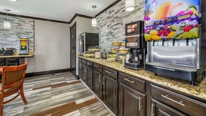 A modern kitchen with a juice dispenser, a coffee machine, and a buffet setup. - Quality Inn Siloam Springs West (Siloam Springs)