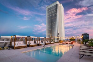 A rooftop pool area with lounge chairs and a large building in the background. - Canopy by Hilton Madrid Castellana (Madrid)