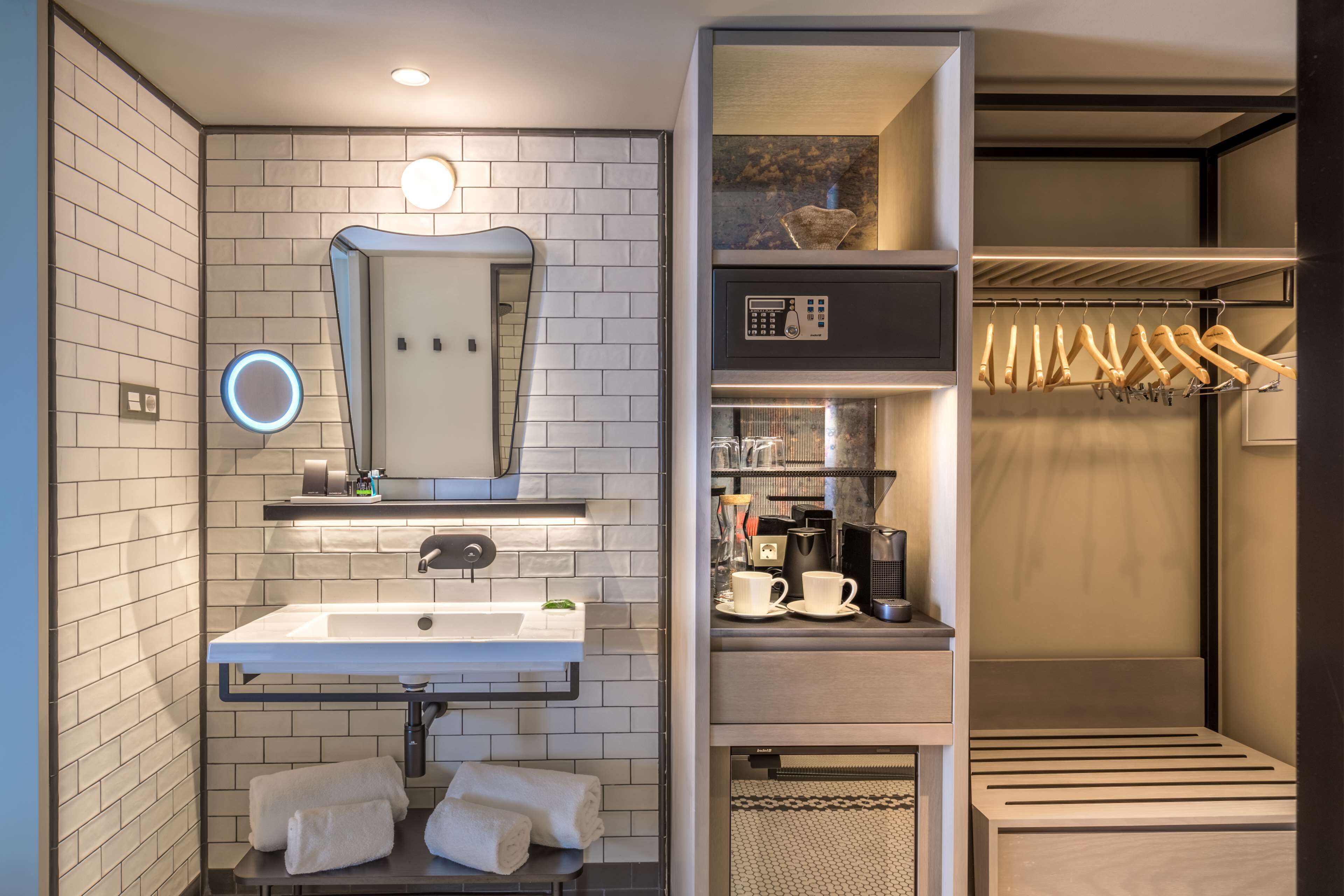 Un baño moderno con lavamanos, espejo y toallero blancos.