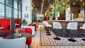 Un área de bar moderna con taburetes altos, suelo estampado y una zona de estar roja.
