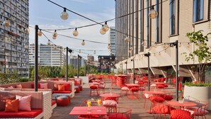 Un espacio al aire libre con mobiliario rojo y luces de guirnaldas.