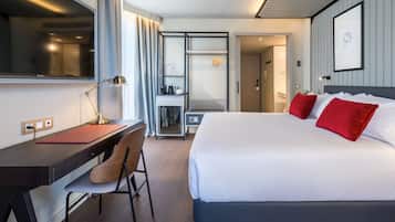 A modern hotel room with a large bed, a desk, and a chair.