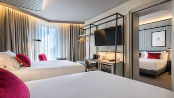 Habitación de hotel con dos camas, un escritorio con silla, un televisor y un armario.