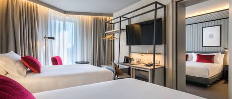 A hotel room with two beds, a desk with a chair, a TV, and a wardrobe.