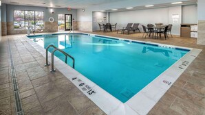 An indoor swimming pool with clear depth markers, a lifeguard chair, and a seating area with tables and chairs. - Hampton Inn Long Island / Commack (Commack)
