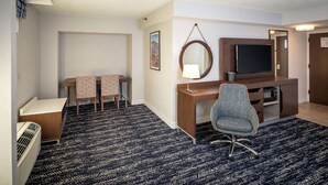 A hotel room with a desk, chair, television, and a small table with a lamp. - Hampton Inn Long Island / Commack (Commack)