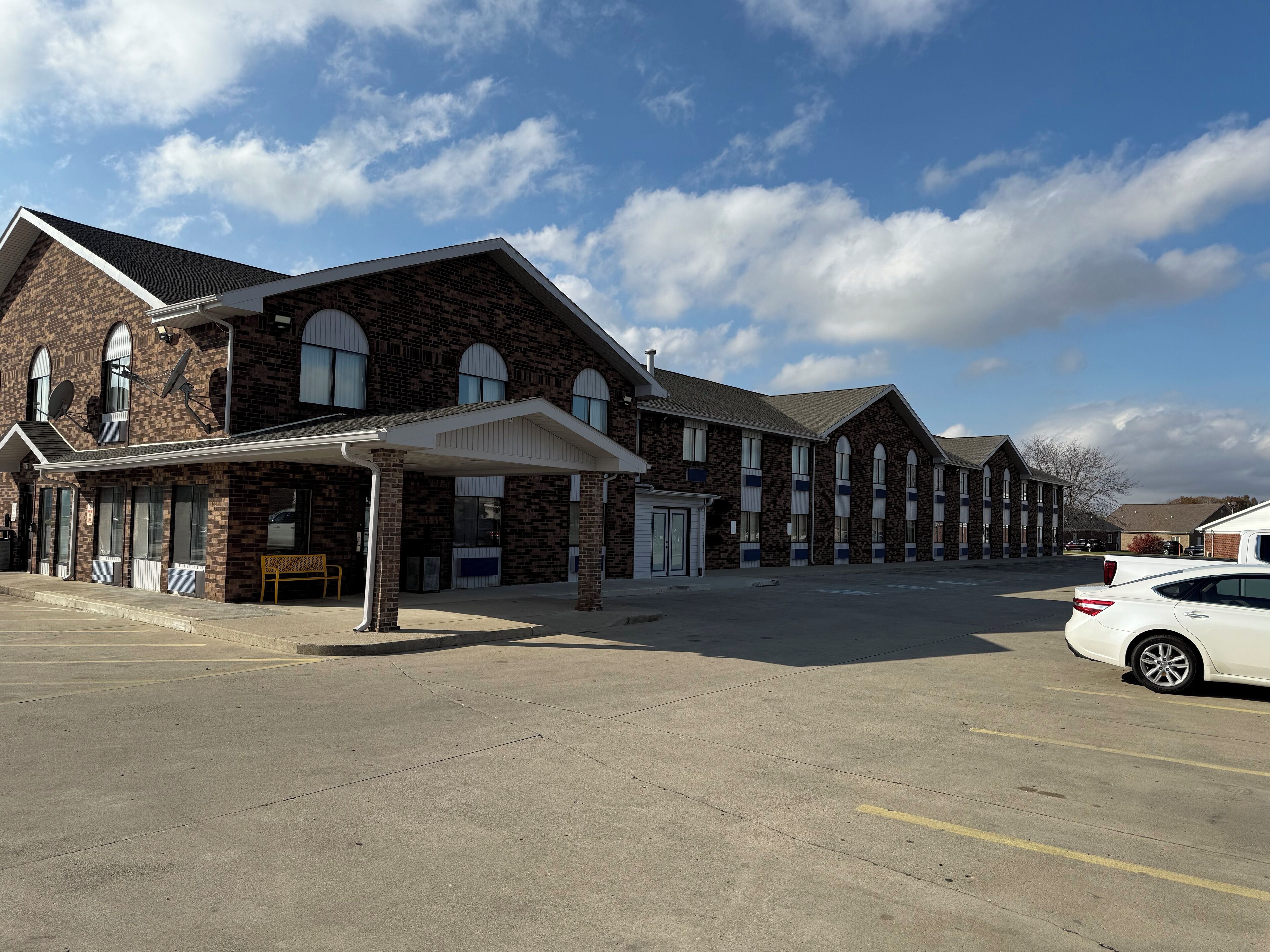 A row of brick buildings with a covered entrance and a parking lot.