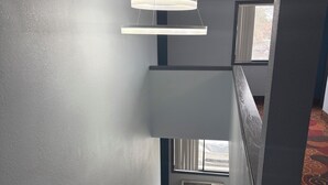 A staircase with a patterned carpet leading to a landing. A modern pendant light hangs above the staircase. - Days Inn by Wyndham Muncie -Ball State University (Muncie)