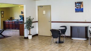 Eine Hotelhalle mit einer Rezeption, einem Blumentopf, einer Tür und einem Poster an der Wand.