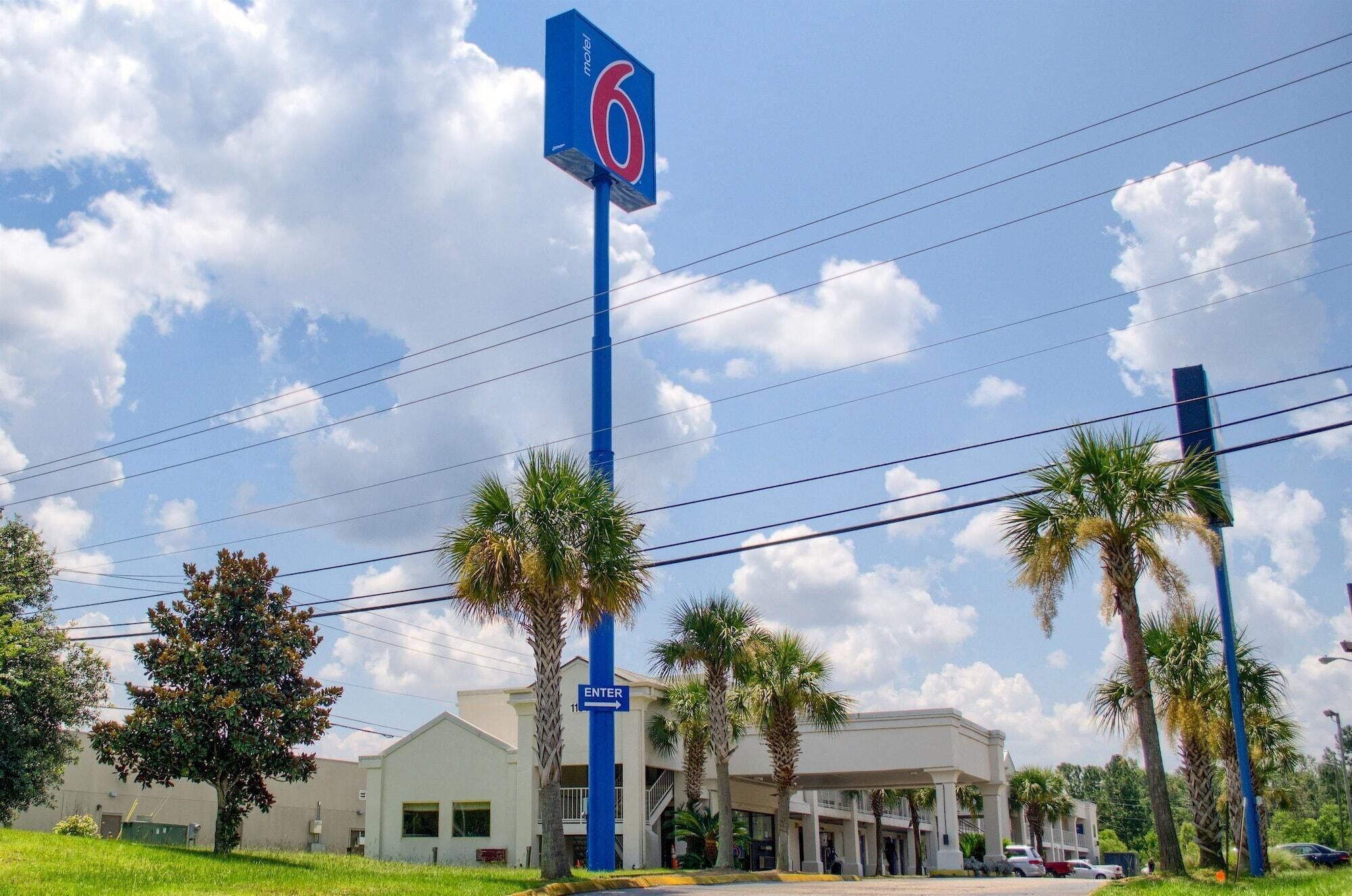 A motel with a prominent '6' sign, a parking lot, and a building with a covered entrance.