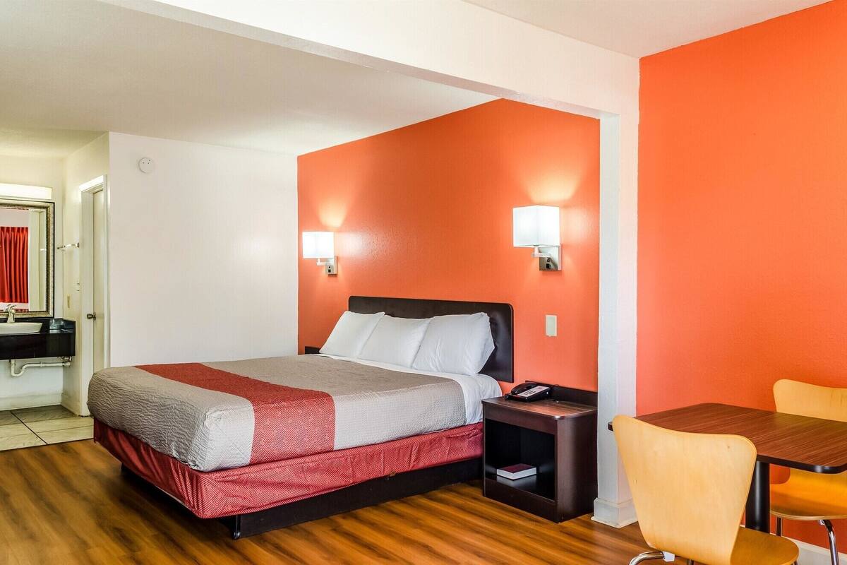 A hotel room with a bed, bedside table, and a chair.
